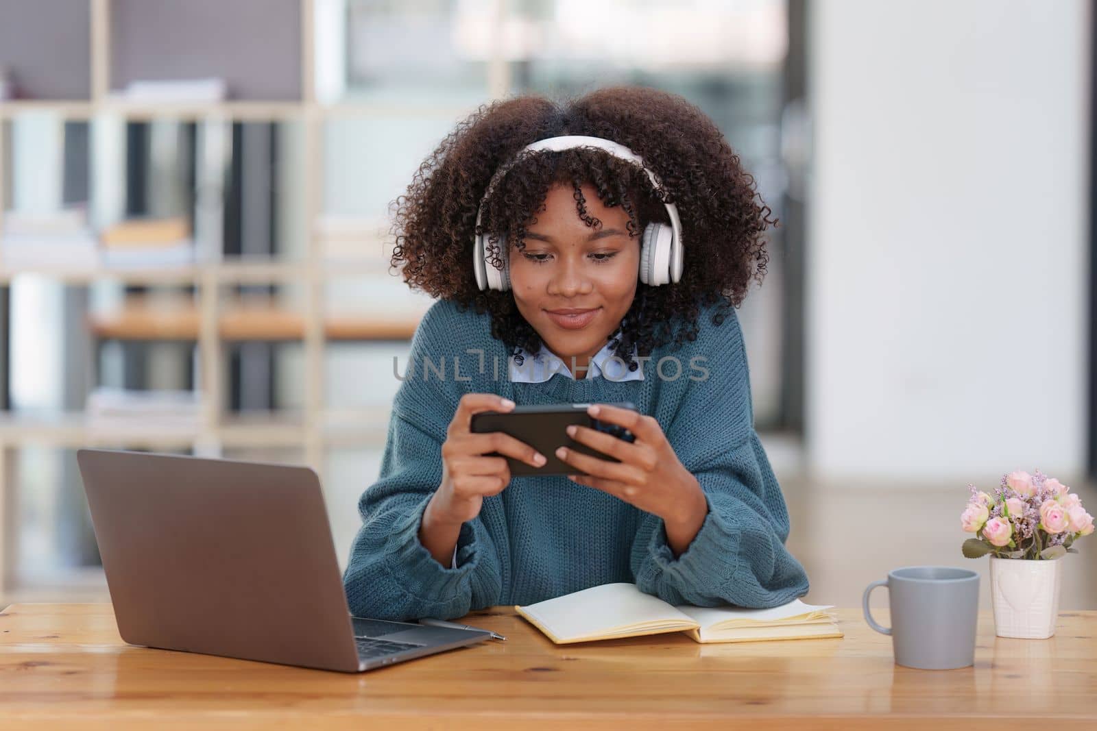 Excited Young black African woman wear headphone and enjoy with game via app on mobile phone
