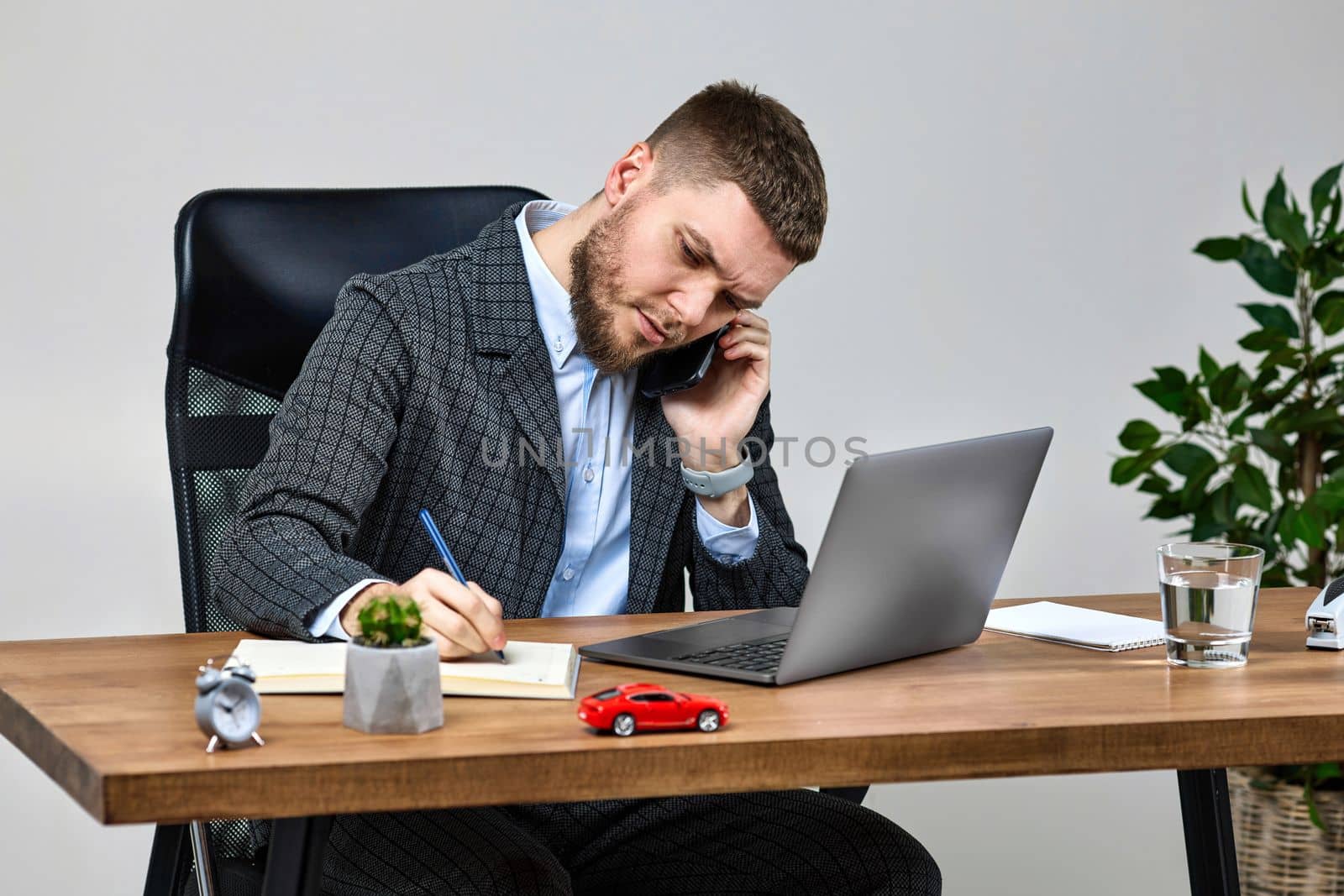 businessman sitting on chair at desk and talking on the phone by erstudio