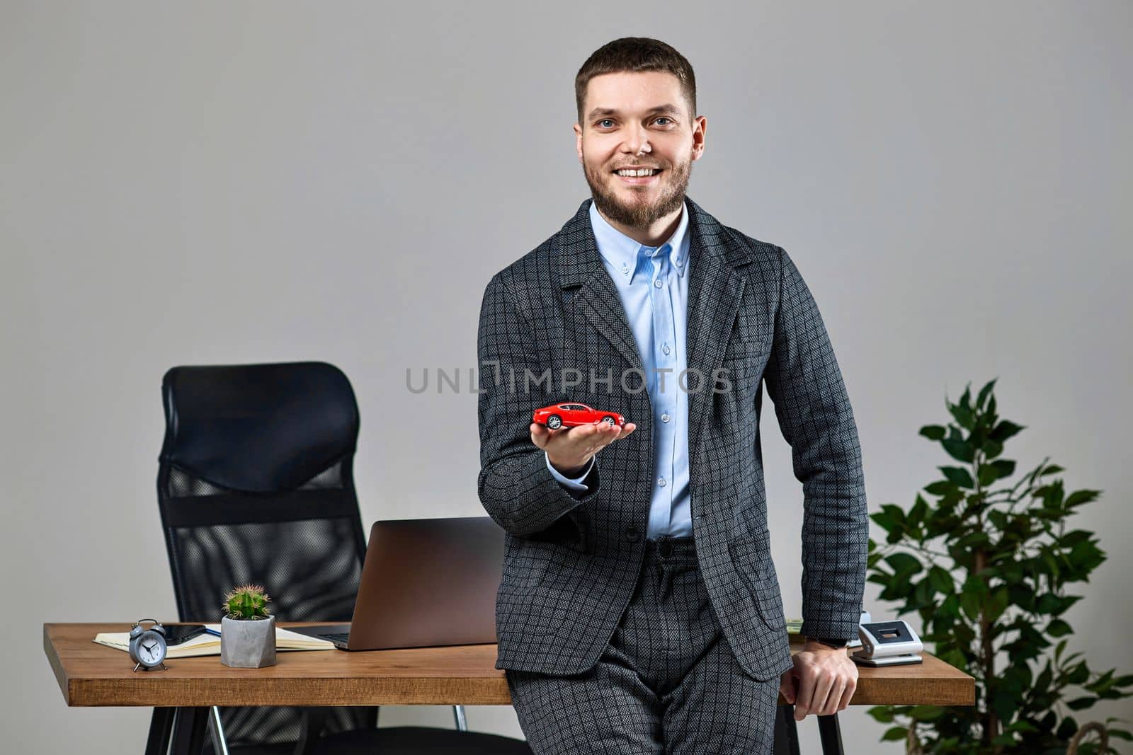 Successful caucasian cheerful man holding a toy car by erstudio