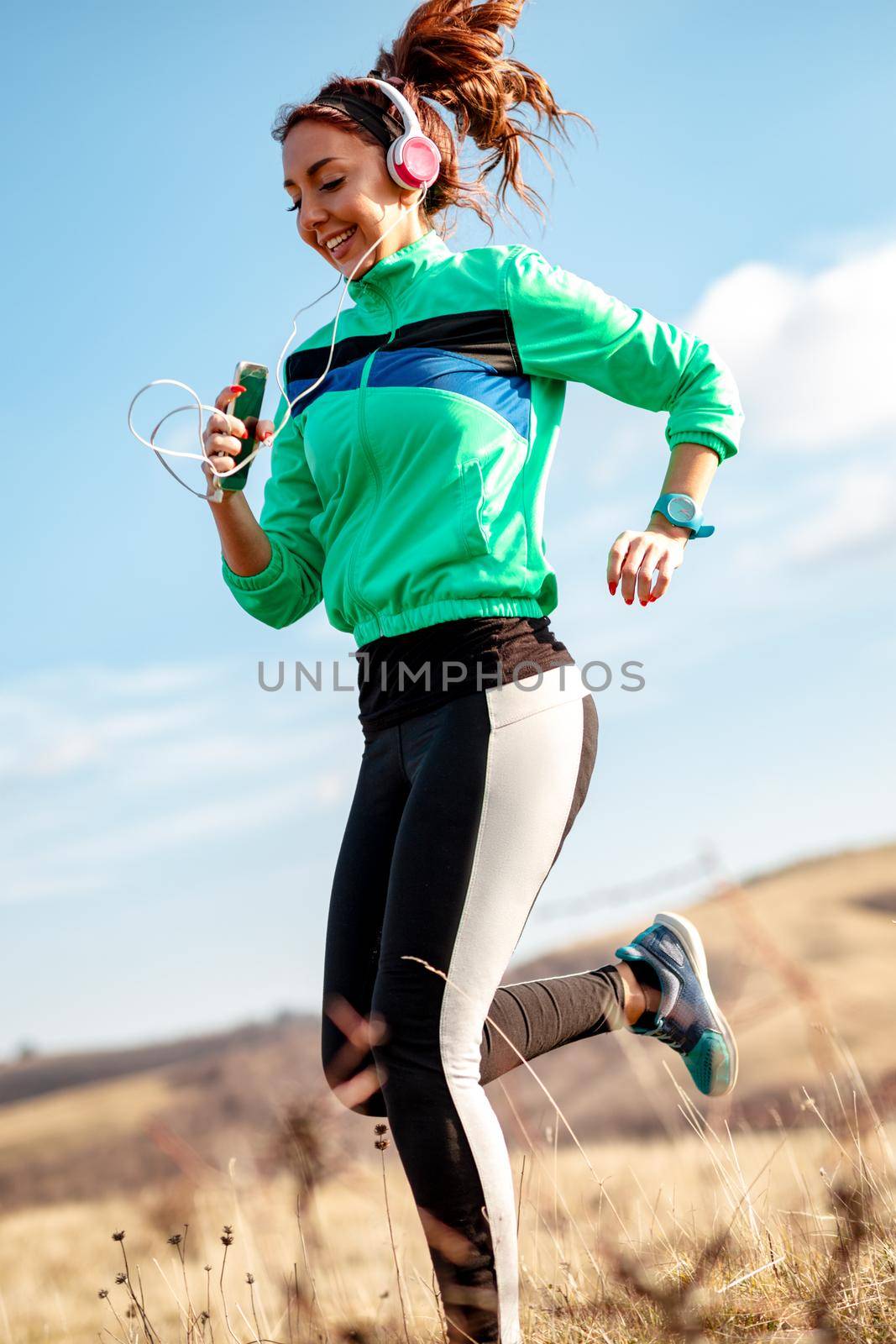 Young sporty woman with headphones jogging in the nature.