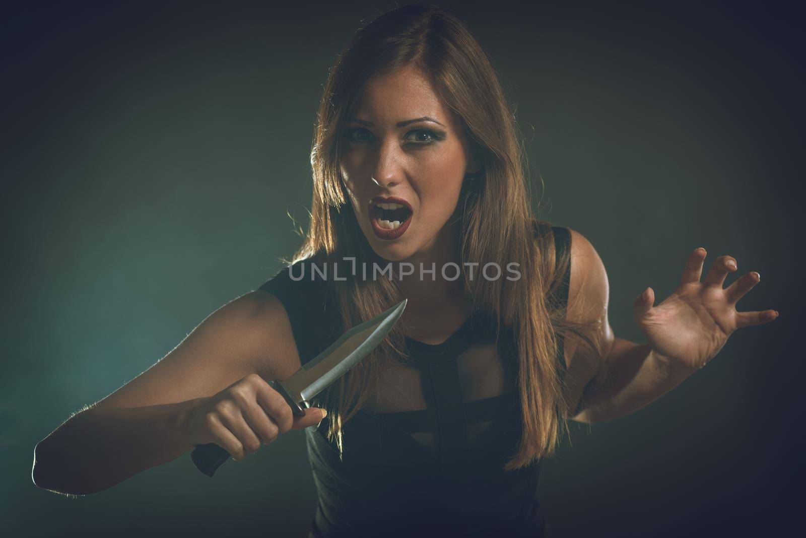 Beautiful dangerous girl with knife want to revenge for violence she experience. Looking at camera.