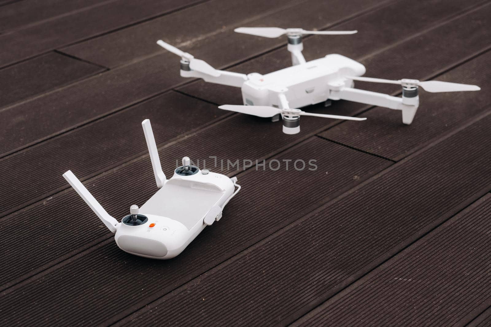 The remote control with the quadcopter is white, and the quadcopter itself is on a wooden background.flight controller on an old wooden background. The view from the top