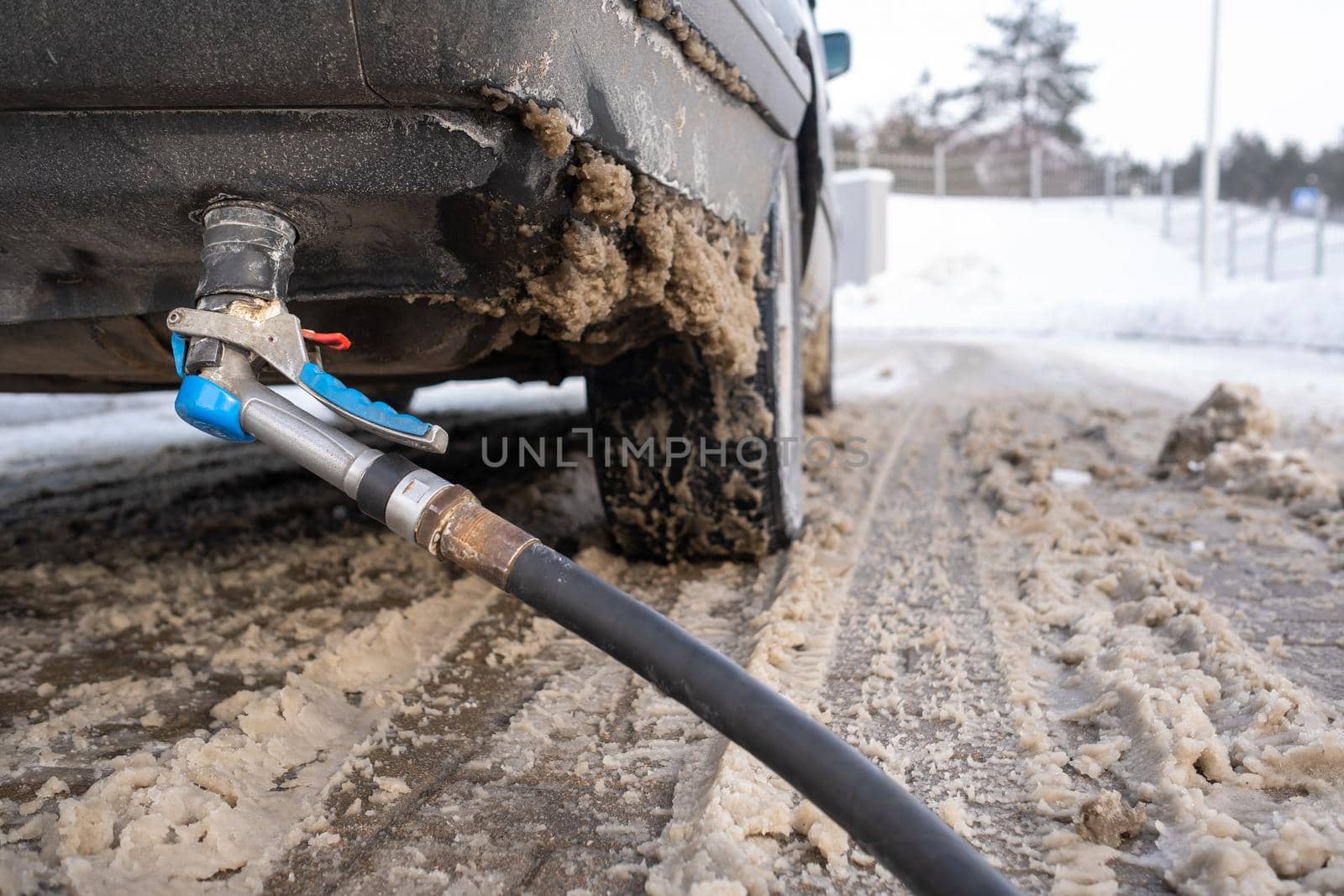 Filling the car from the bottom of the bumper with gas in the winter at the gas station.