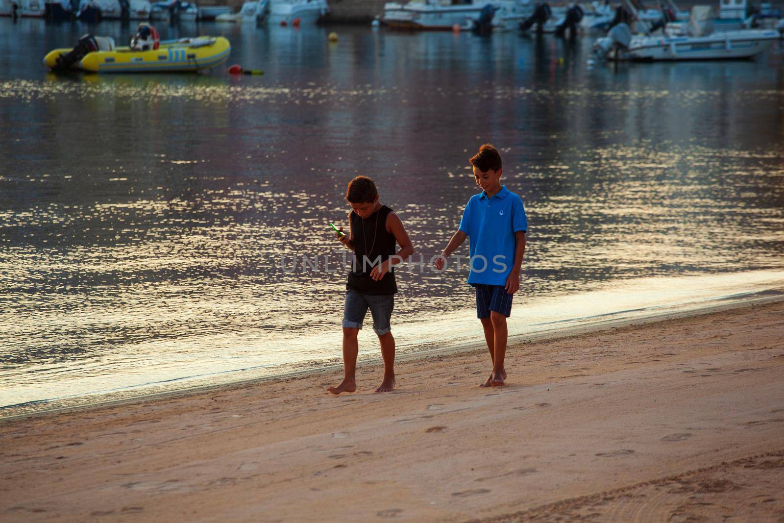 LAMPEDUSA, ITALY - AUGUST, 01: Two little boys play in the shoreline of Lampedusa at sunset on August 01, 2018