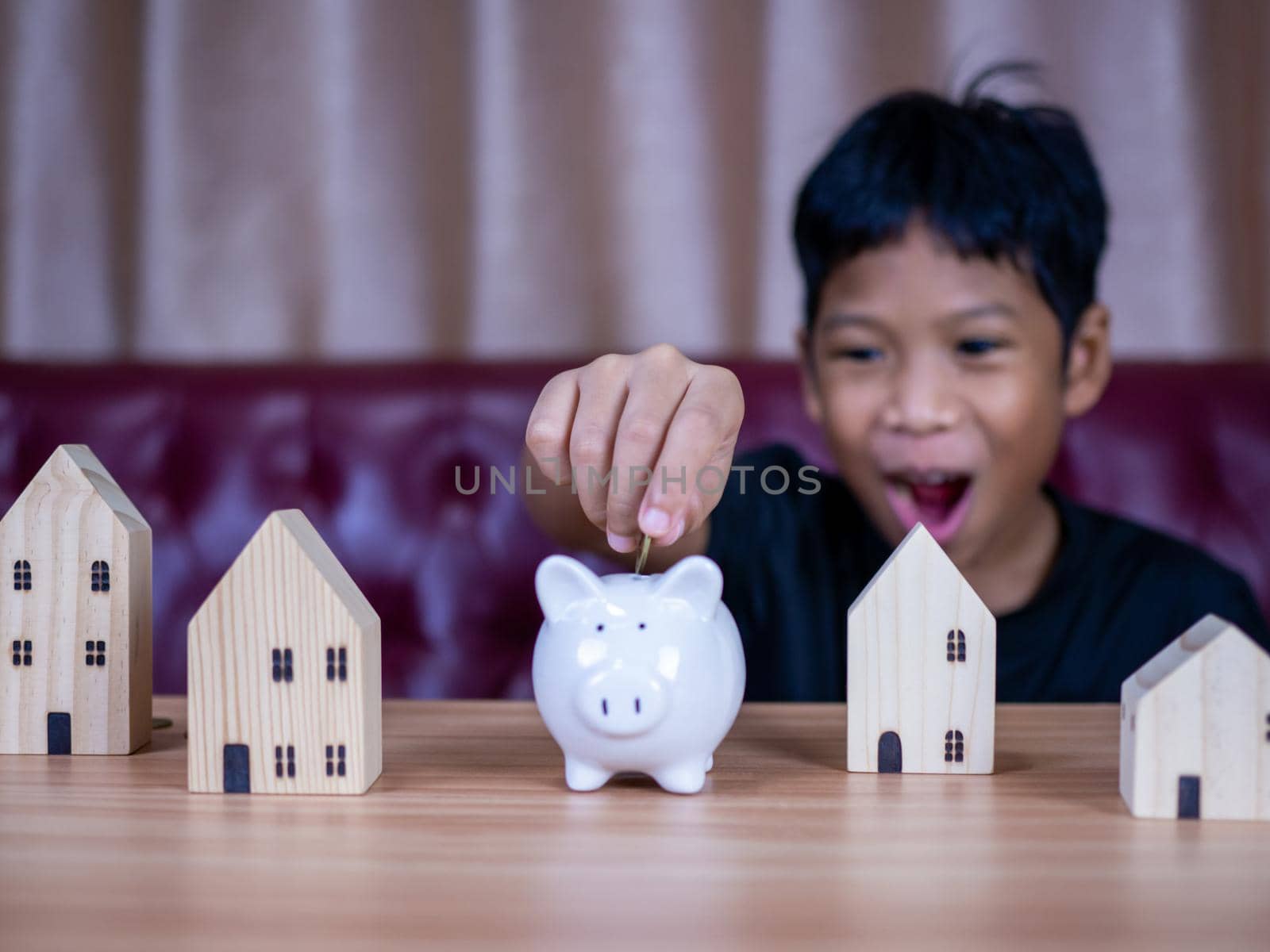 Boy saving money in a white pig piggy bank.Saving concept. Saving for the future. by Unimages2527