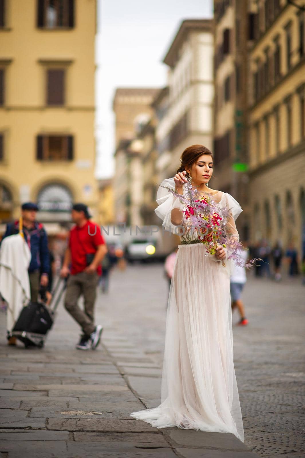 a bride in a wedding dress with a Venetian mask in her hands in Florence.Italy by Lobachad