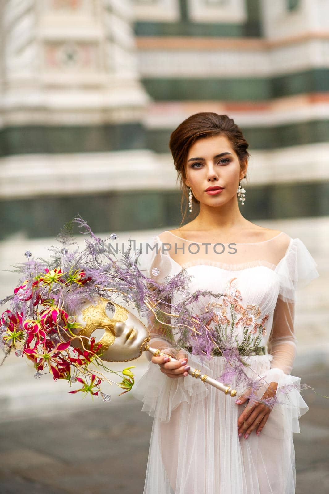 a bride in a wedding dress with a Venetian mask in her hands in Florence.Italy by Lobachad