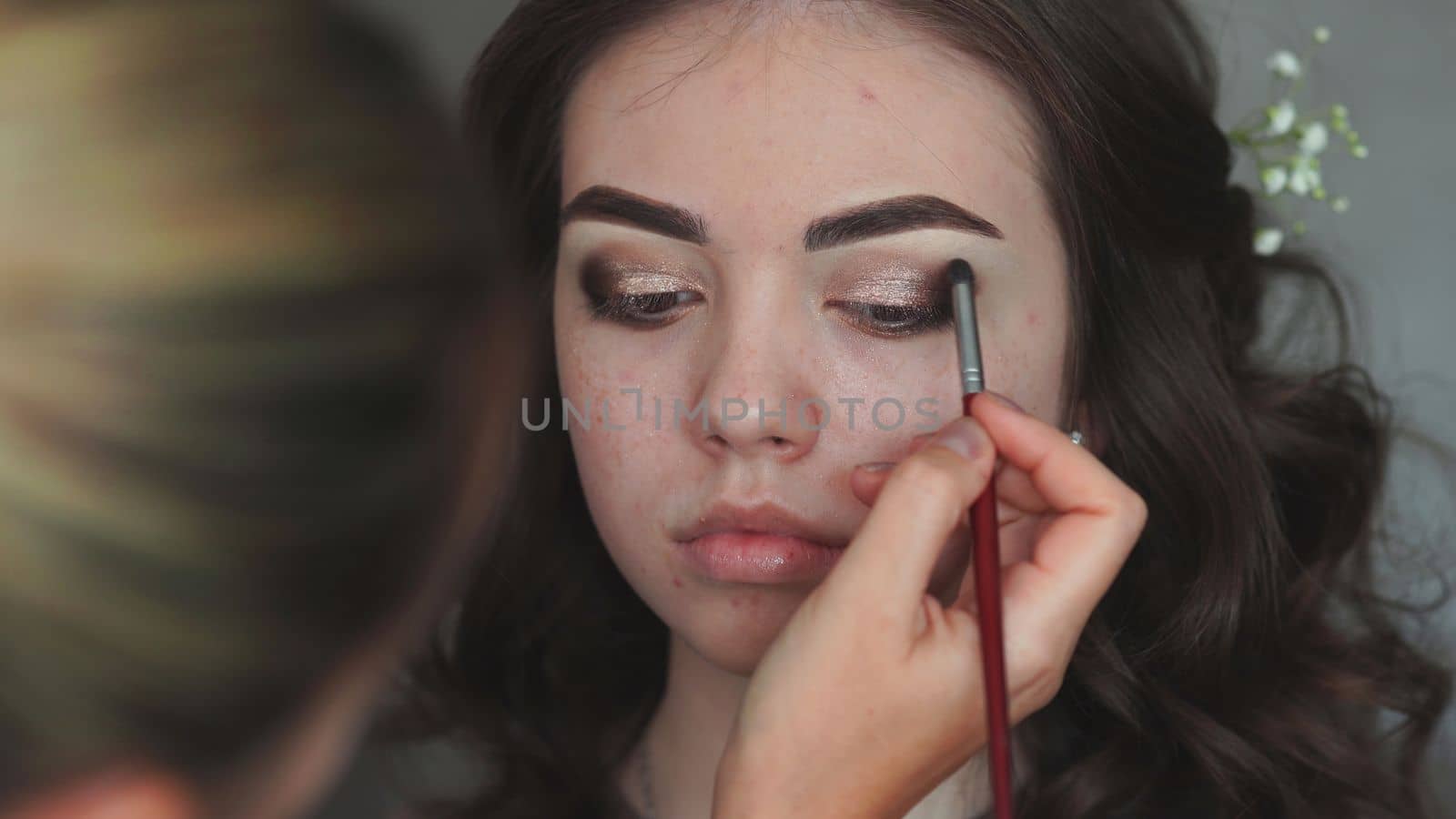 Makeup artist paints the eyelids of a girl model