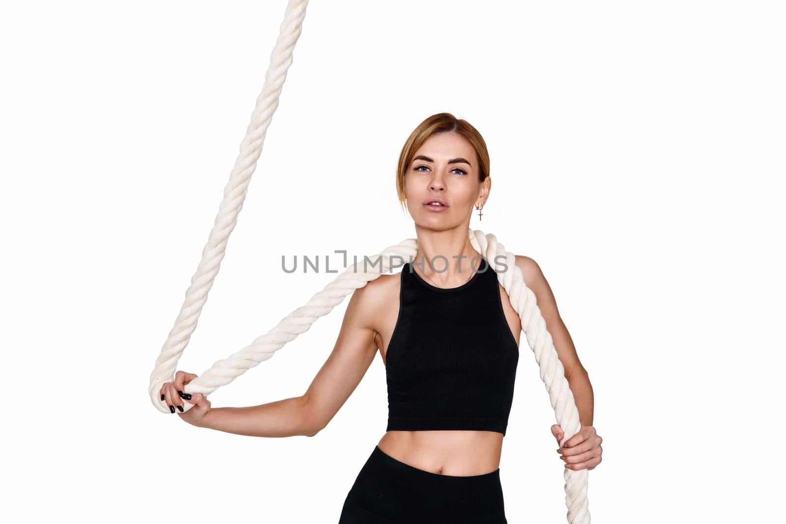 Sporty slim blonde woman in sportswear with rope on white background