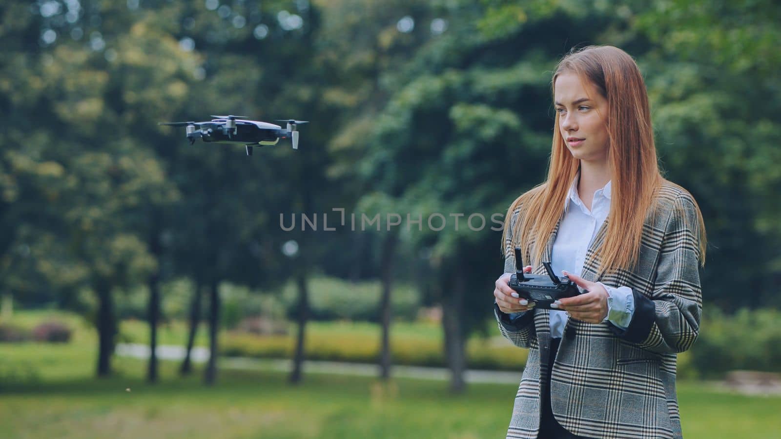 A cute girl controls a drone in the park