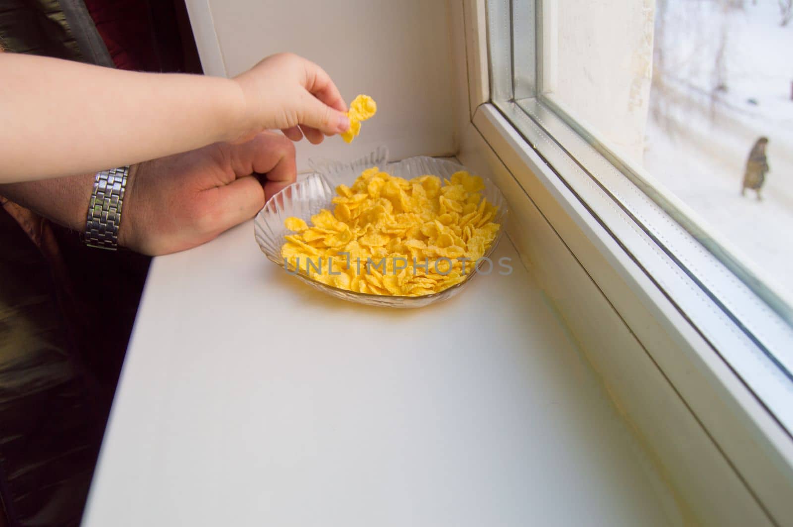 The child reached for the cereal, a little boy and a grown man standing at the window.