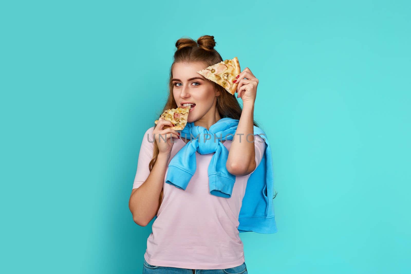 happy woman holding two slice of fresh pizza on blue background.