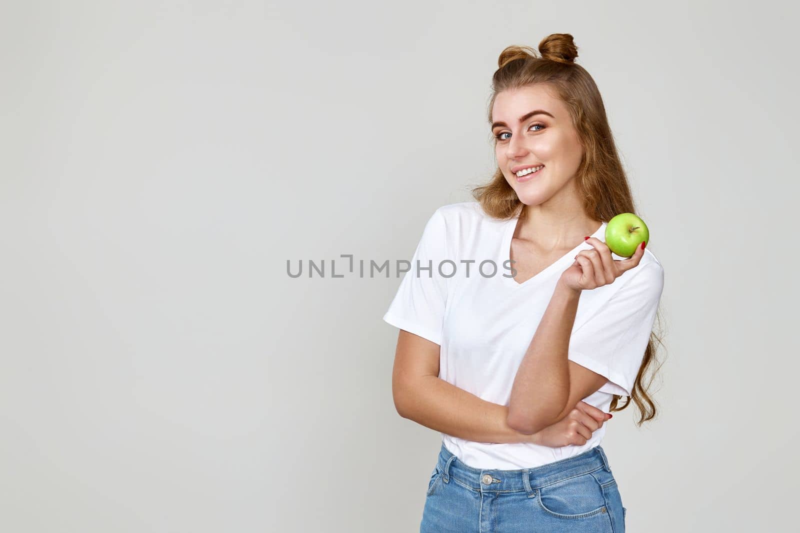 smiling pretty girl holding green apple isolated on studio background. copy space