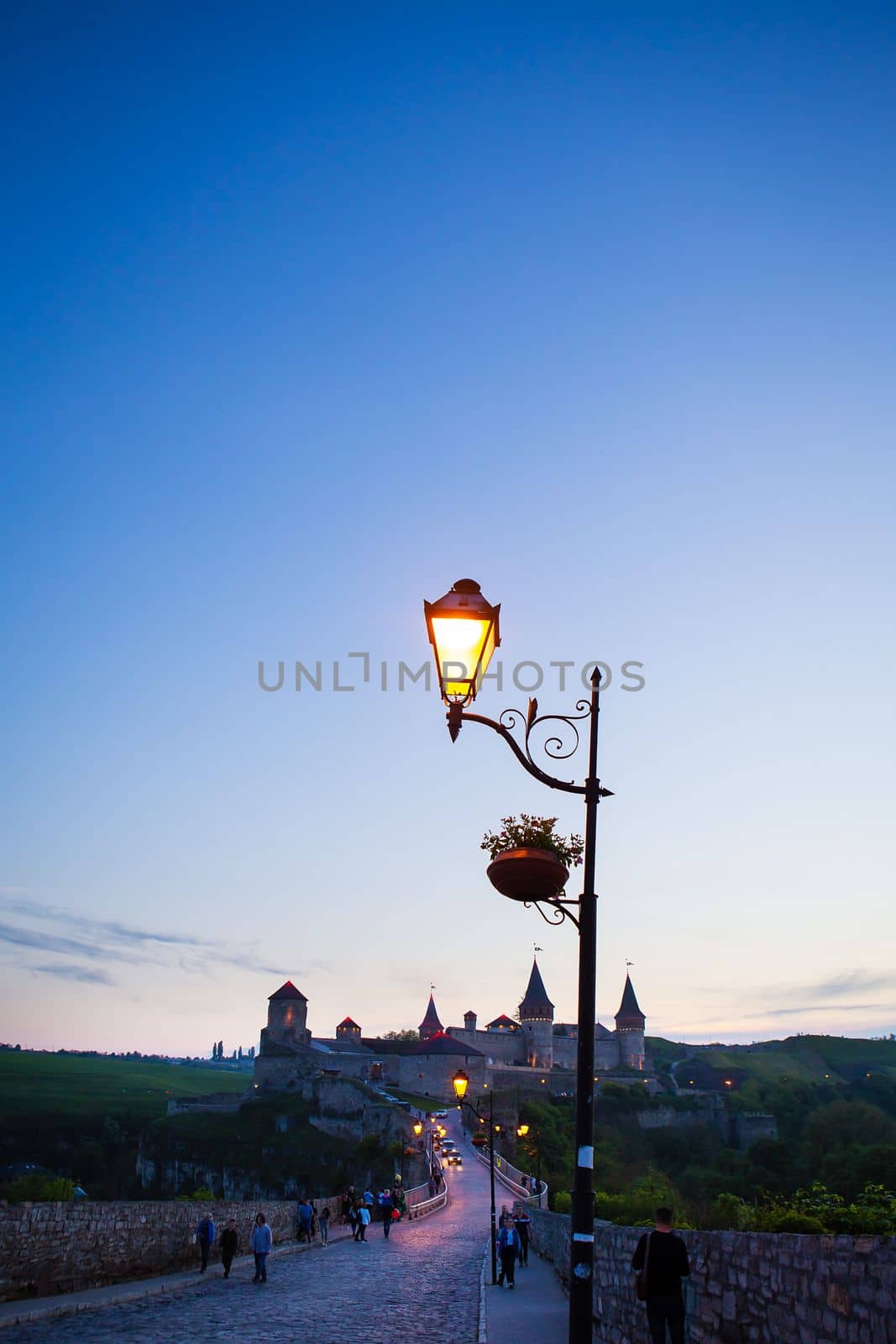 Kamianets-Podilskyi is a romantic city, a beautiful view of the evening city, lanterns illuminate the bridge, lantern close-up. A picturesque summer view of the ancient castle-fortress in Kamianets-Podilskyi, Khmelnytskyi region, Ukraine
