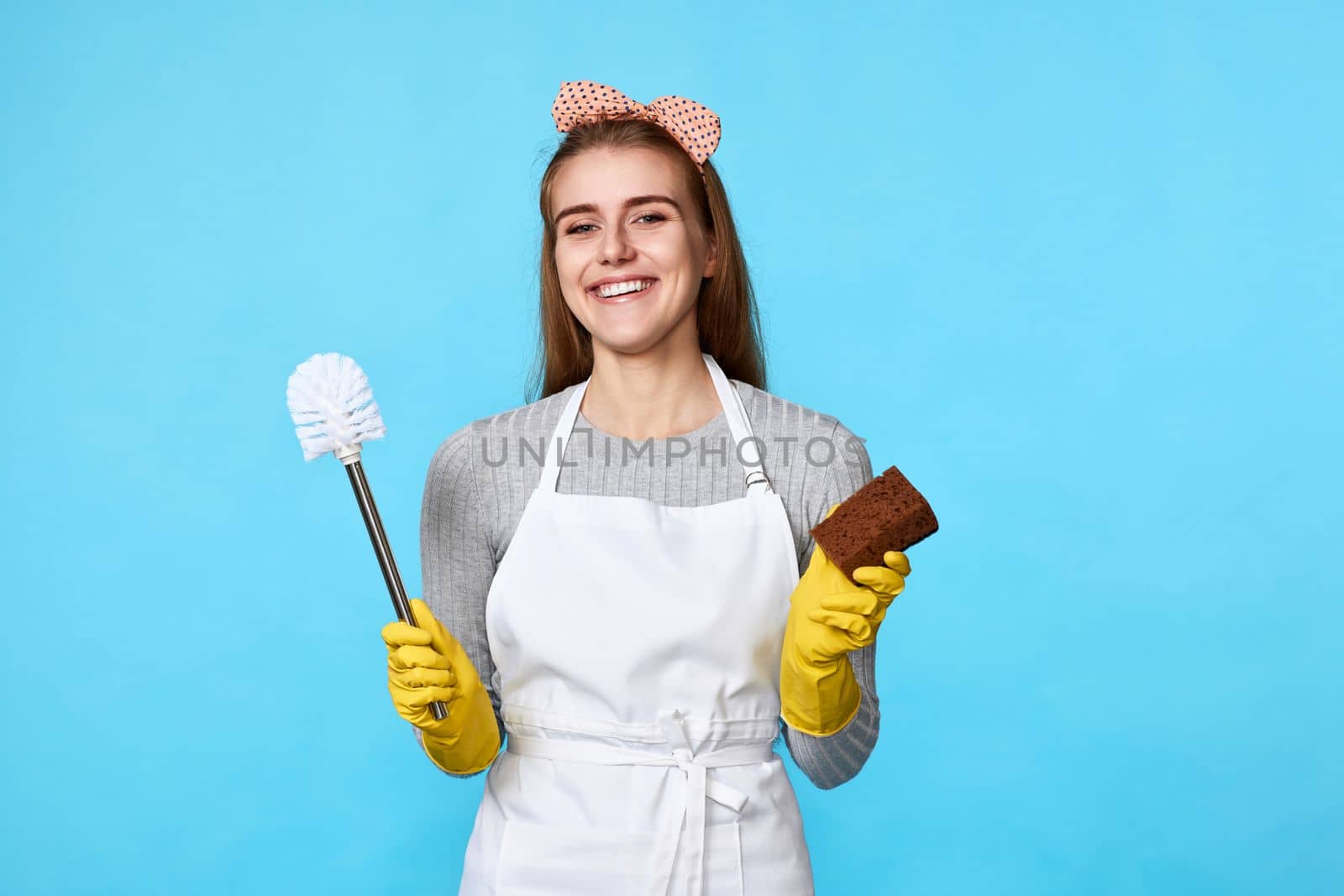 happy woman in rubber gloves cleaning with sponge and toilet brush on blue background.