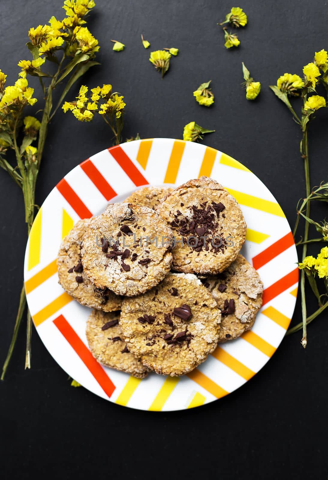 Oatmeal cookies with chocolate on a plate with bright yellow flowers. by sfinks