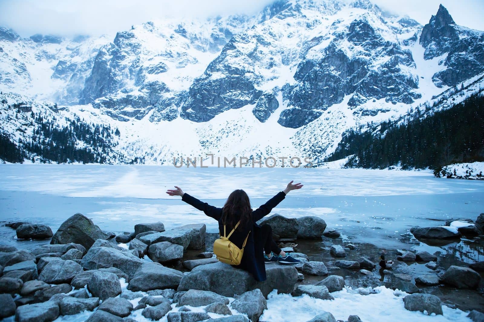 Picturesque and beautiful view of the mountains. Sea eye. The girl is sitting on a stone