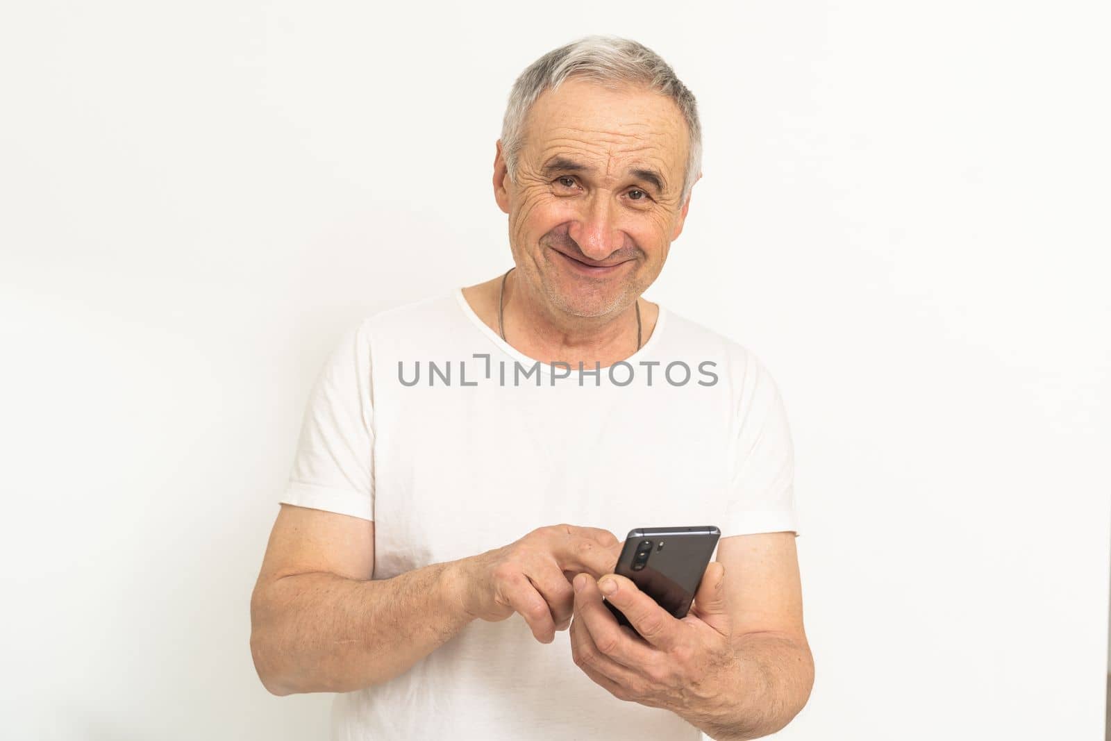 Happy retired man using a smartphone. by Andelov13