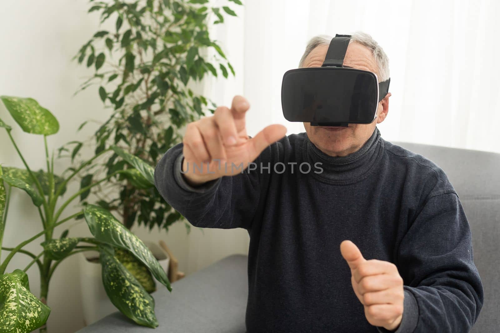 technology, augmented reality, gaming, entertainment and people concept - senior man with virtual headset or 3d glasses playing videogame at home. by Andelov13