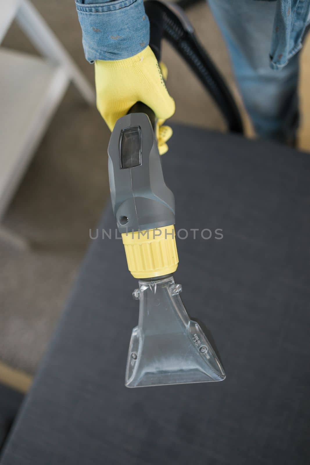 Man cleaning couch with washing vacuum cleaner