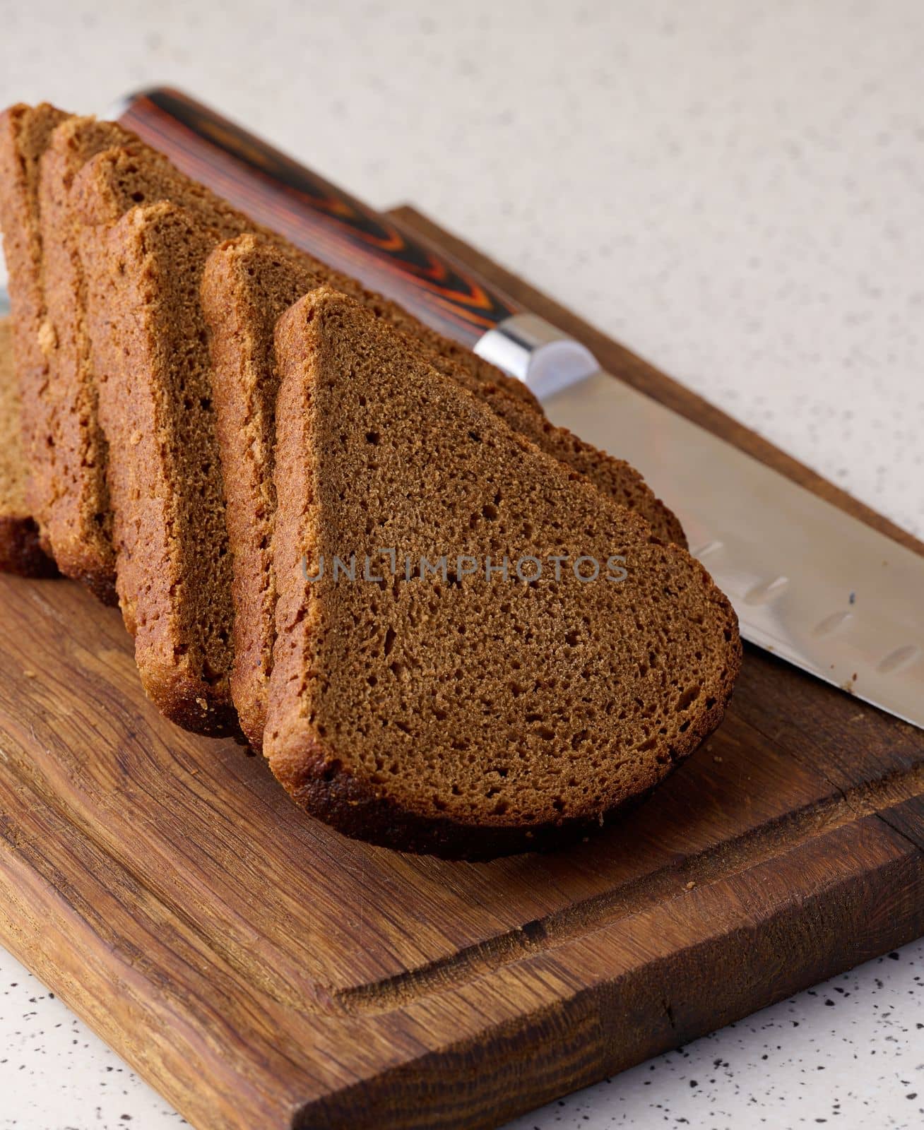 Triangular rye piece of bread on a wooden cutting board by ndanko