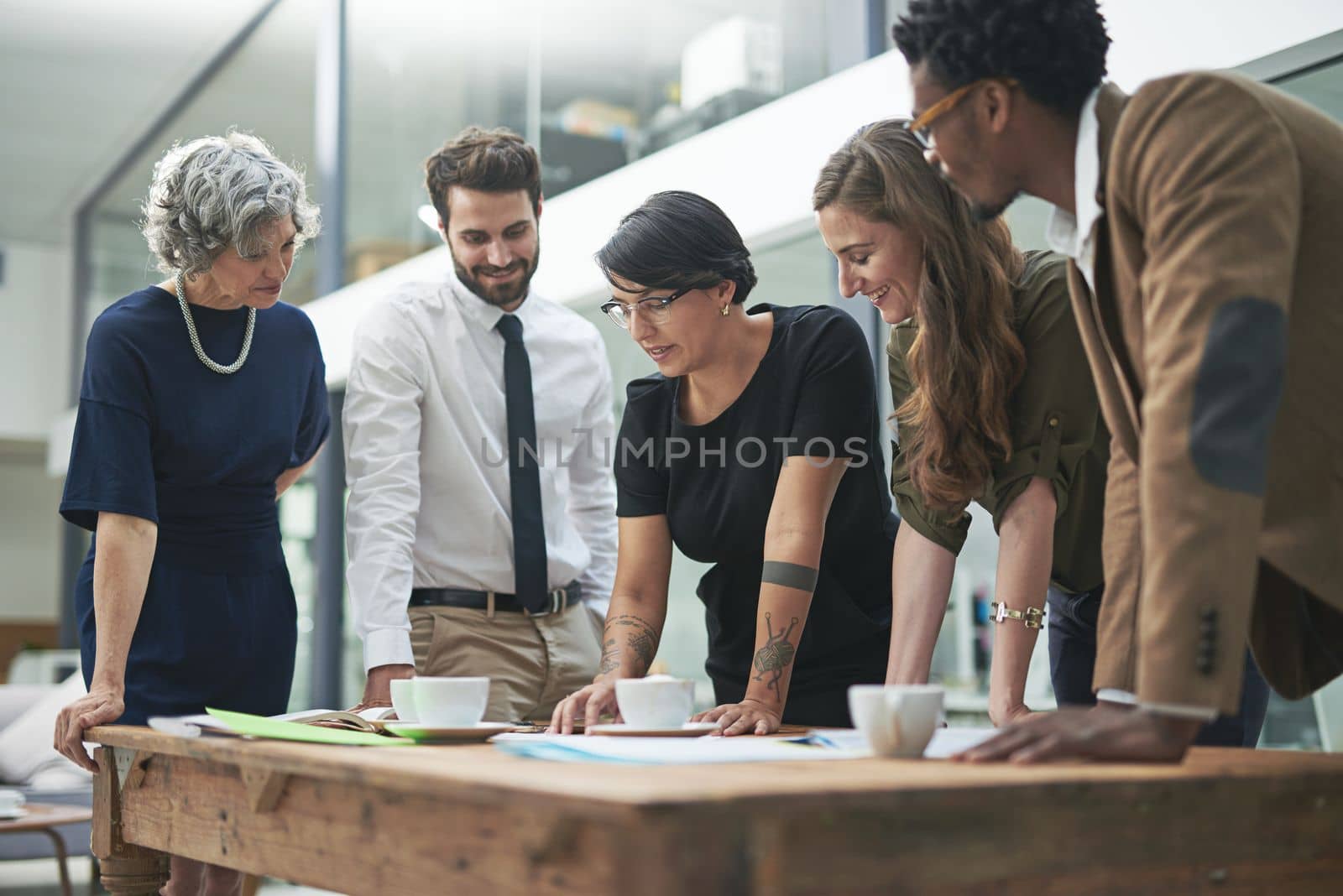 Planning their assault on the deadline. a diverse group of businesspeople having a meeting in their modern office. by YuriArcurs