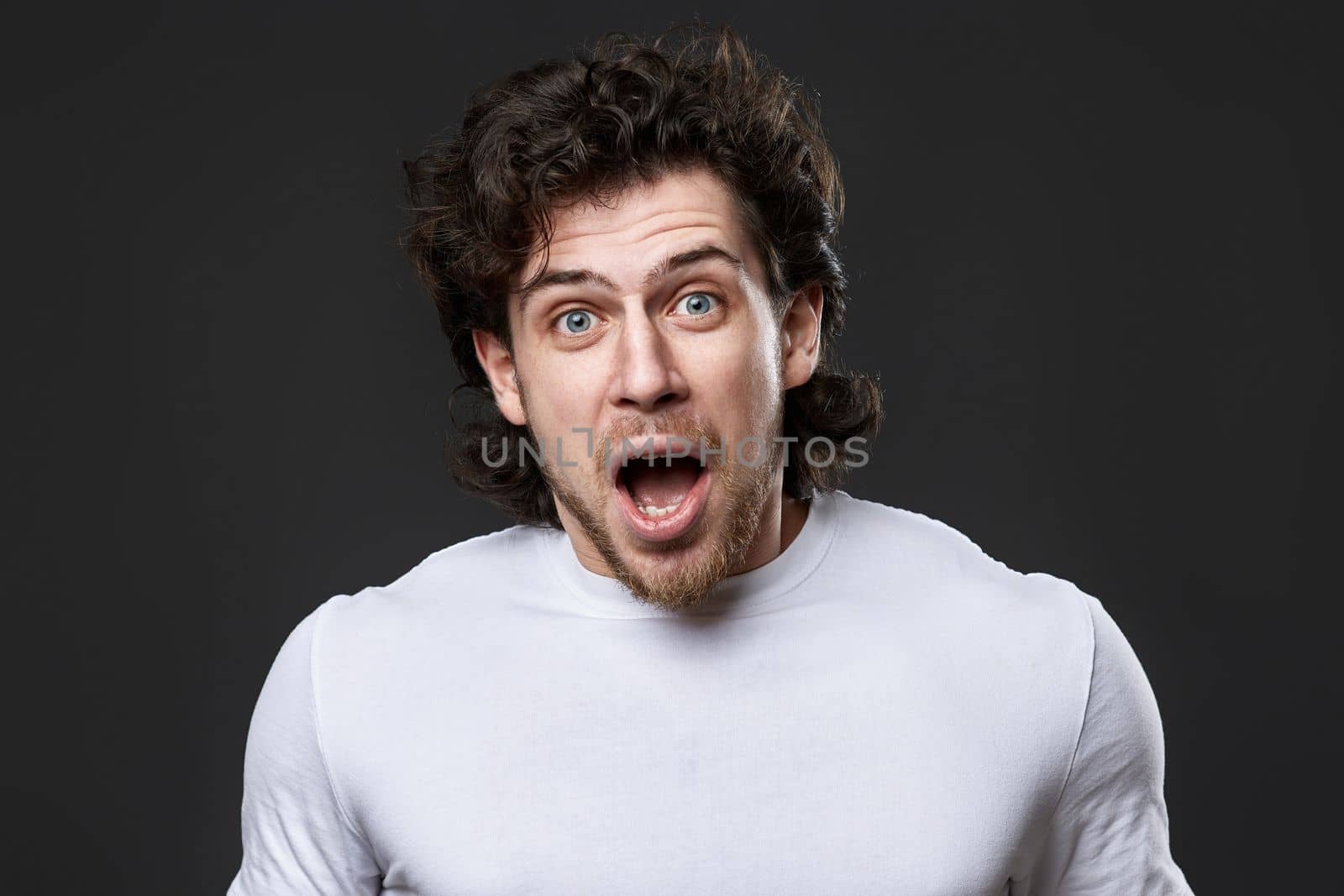 portrait of surprised young bearded man on gray backround