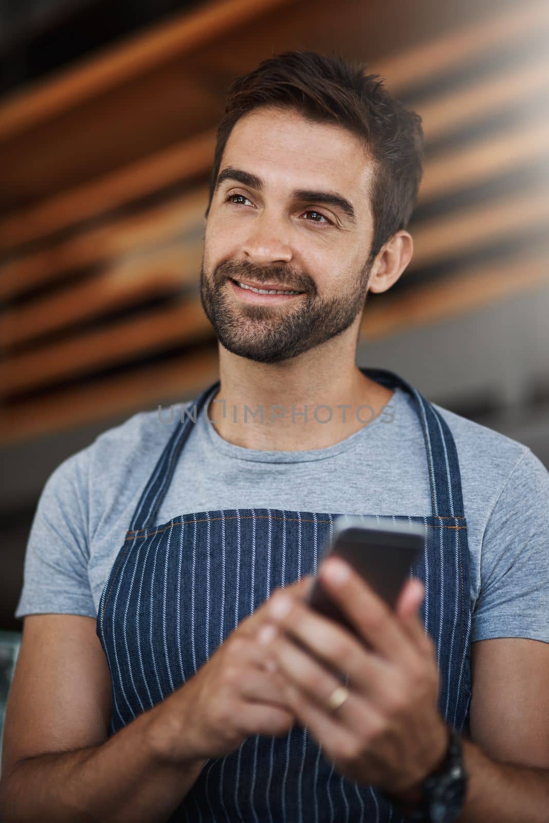 The smartest small business owner around. a young man using a mobile phone while working at a coffee shop