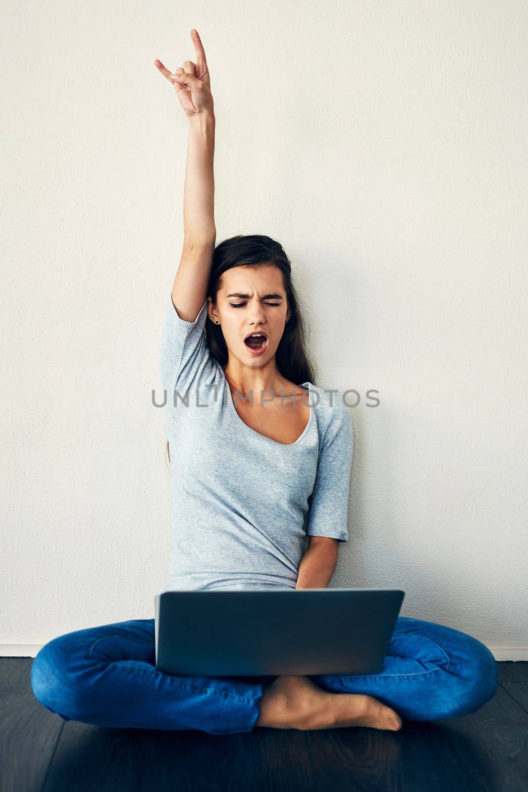 I finally got those tickets to that rock concert. a young woman sitting on the floor while using a laptop