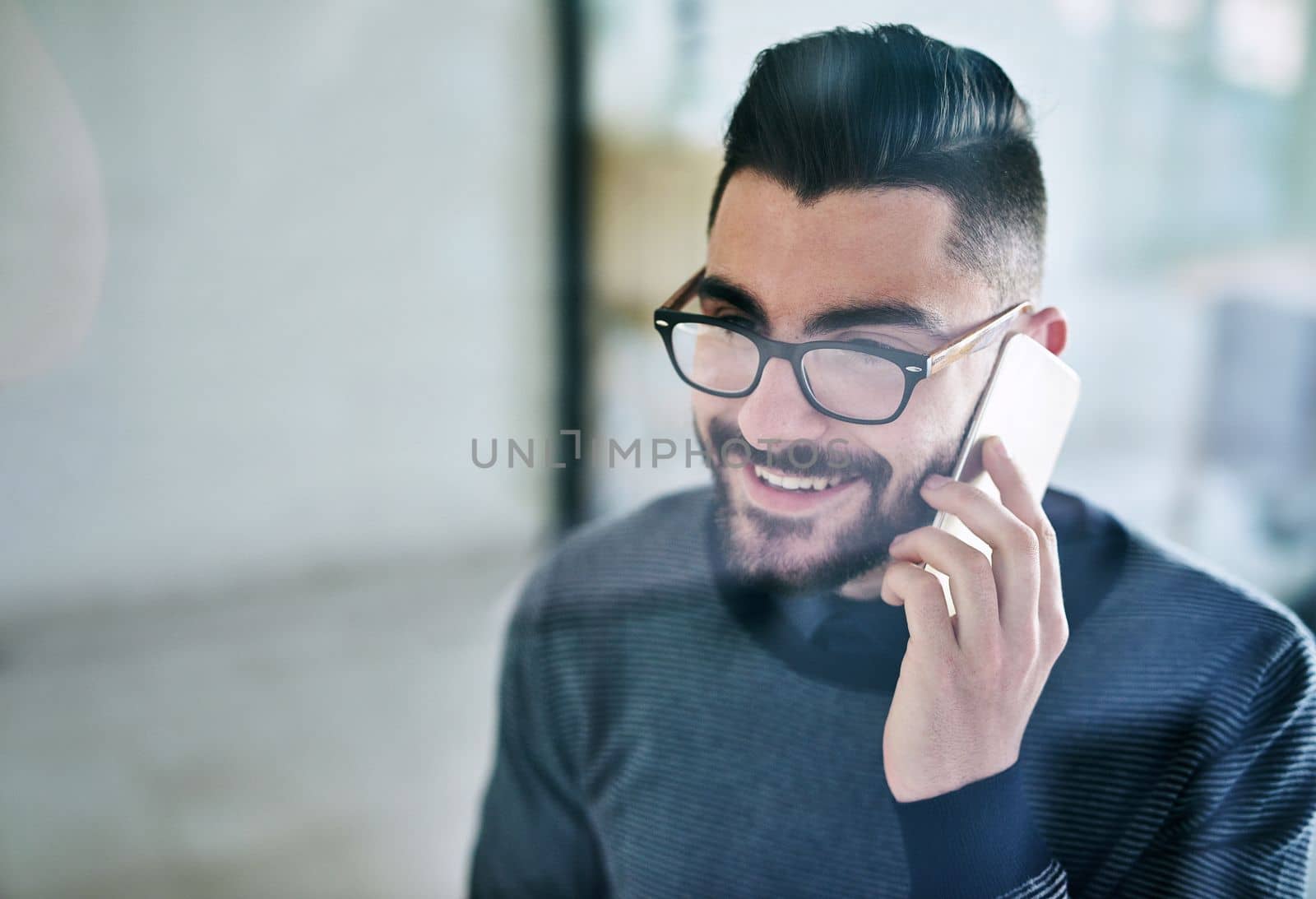 Growing his business connections. a young designer talking on a cellphone in an office