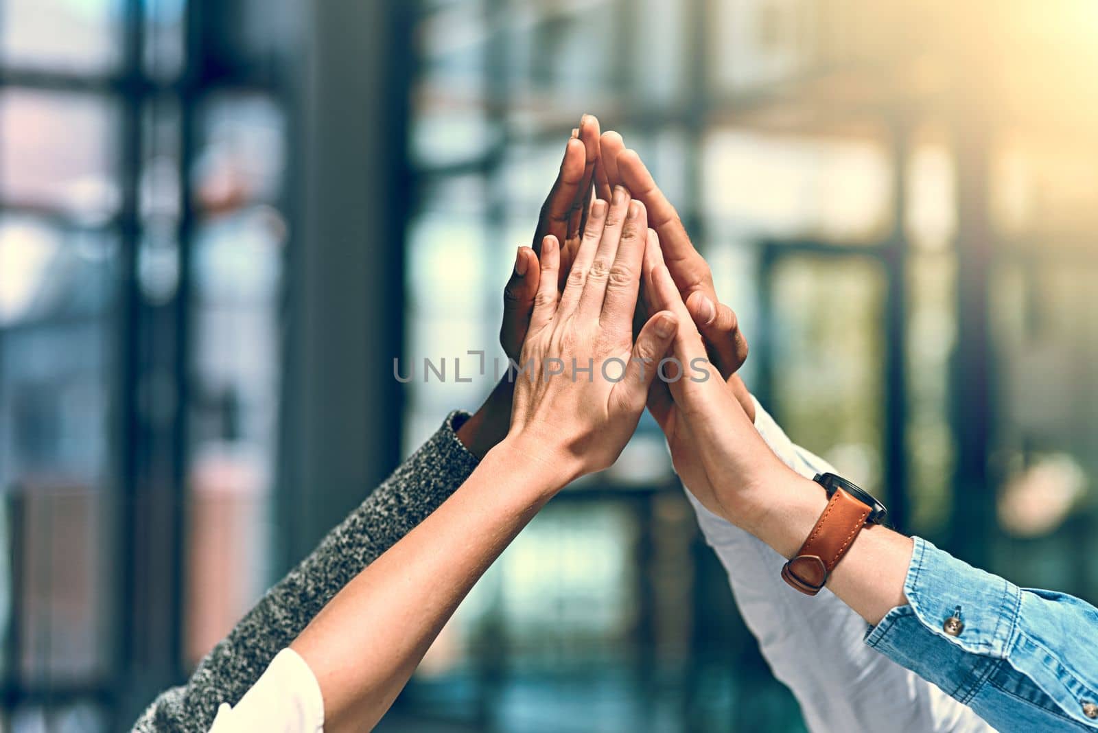 Achieving success together. a group of unrecognizable businesspeople high fiving. by YuriArcurs