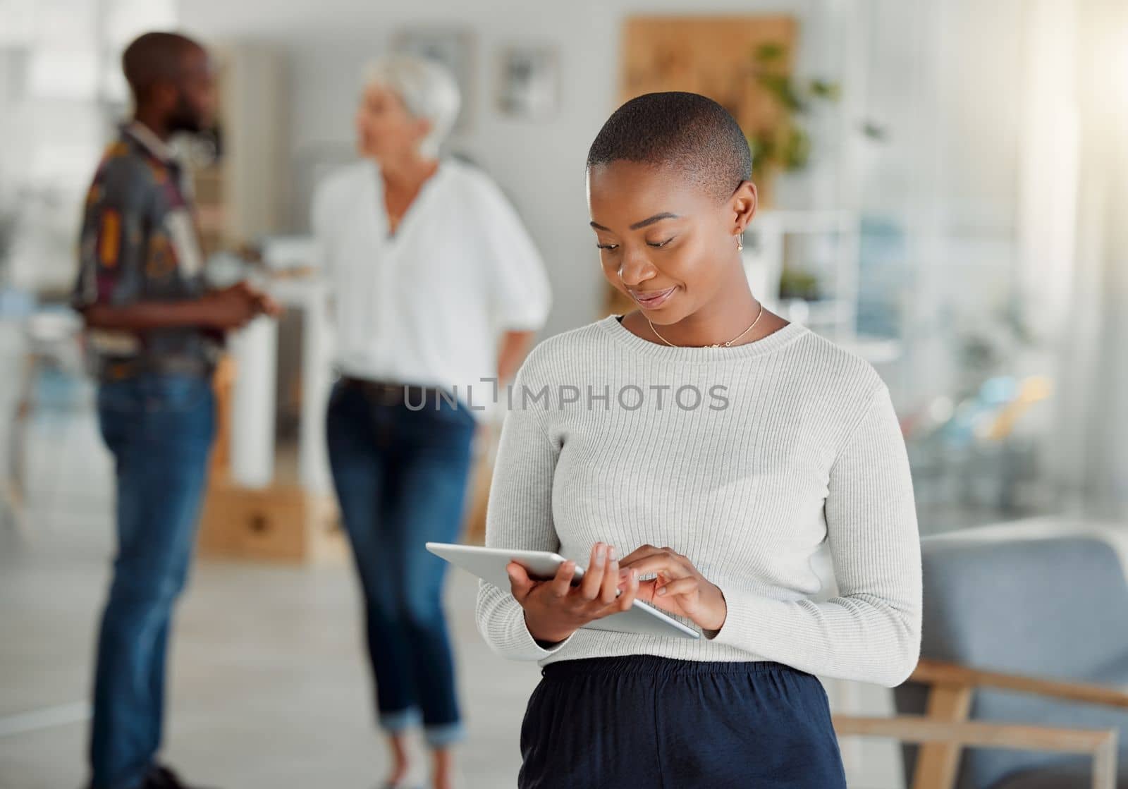 Young happy african american businesswoman holding and using a digital tablet at work. Black female businessperson working on a digital tablet at work. Black woman using social media and browsing onl.