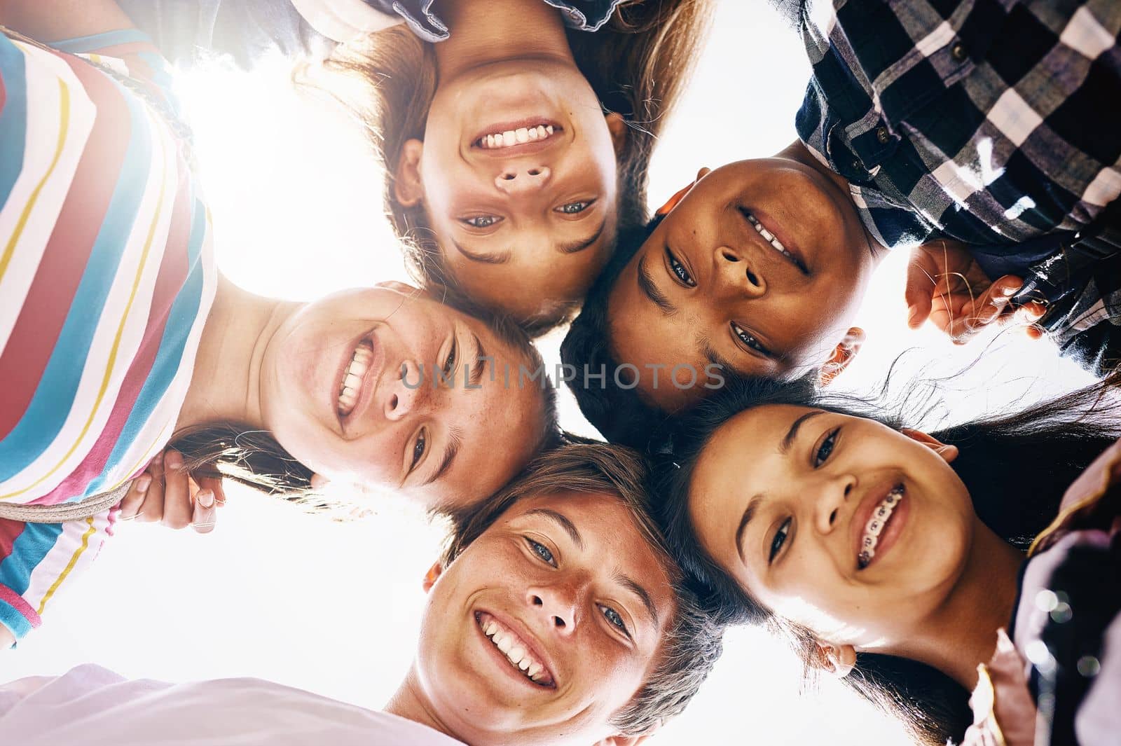 They always find a reason to smile. Low angle portrait of a group of diverse schoolchildren standing in a huddle. by YuriArcurs