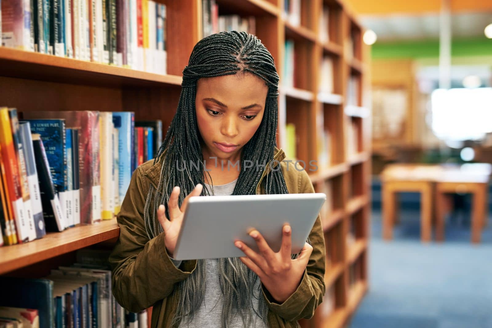 Education through the digital sphere. a university student using a digital tablet in the library at campus