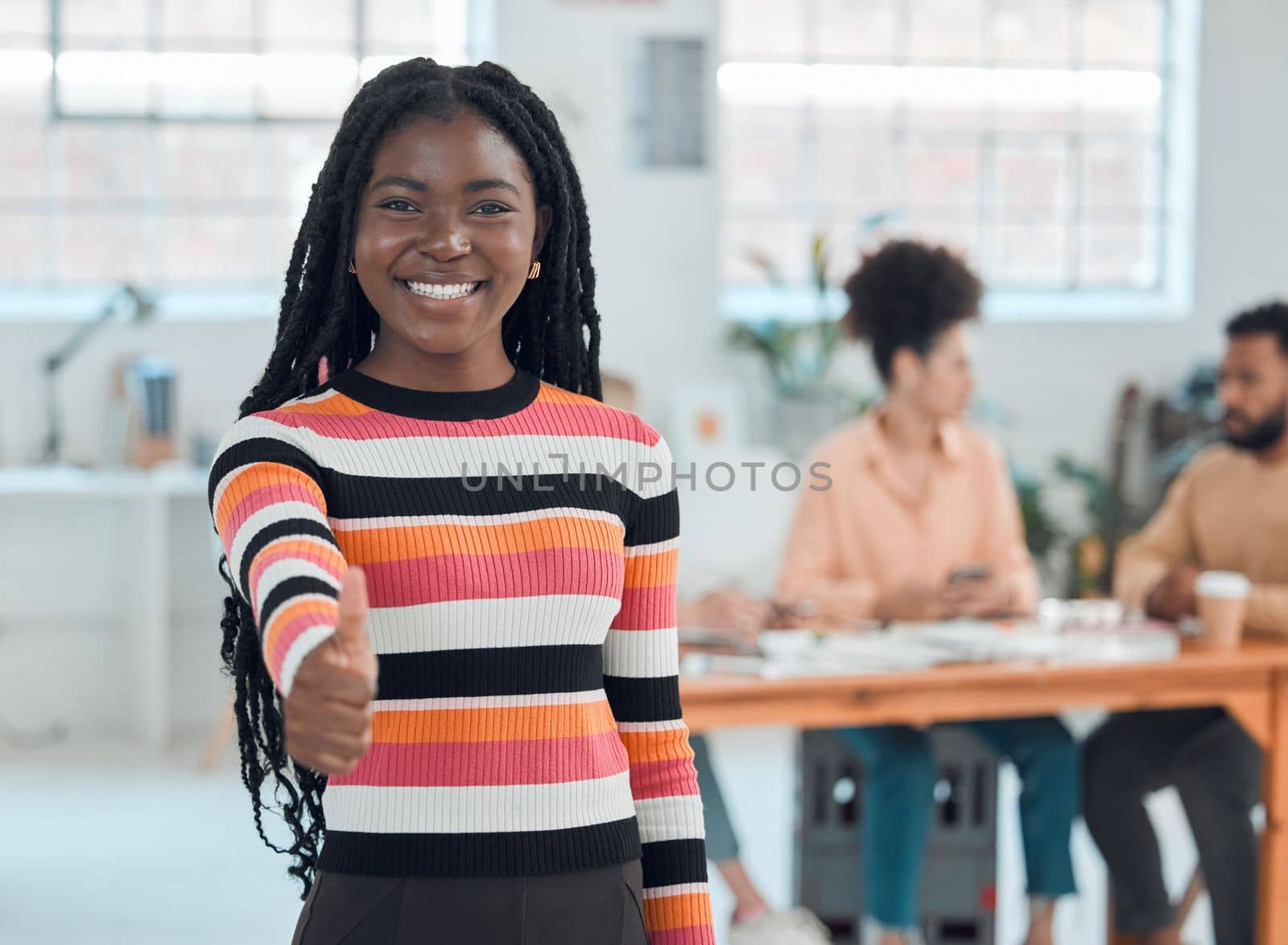 Portrait of a young happy african american businesswoman showing a thumbs up in an office at work. Cheerful black female businessperson showing support with a hand gesture.