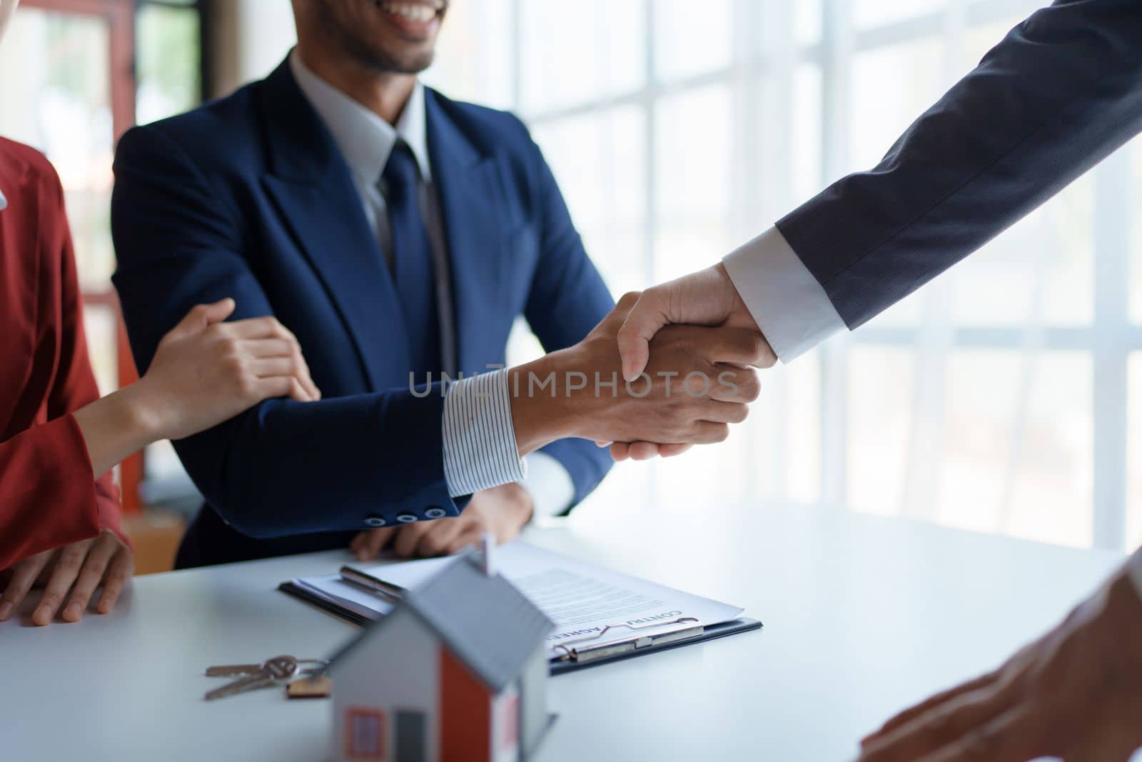 Asian real estate agent shaking hands handing over house and keys to his client's house after client sign contract