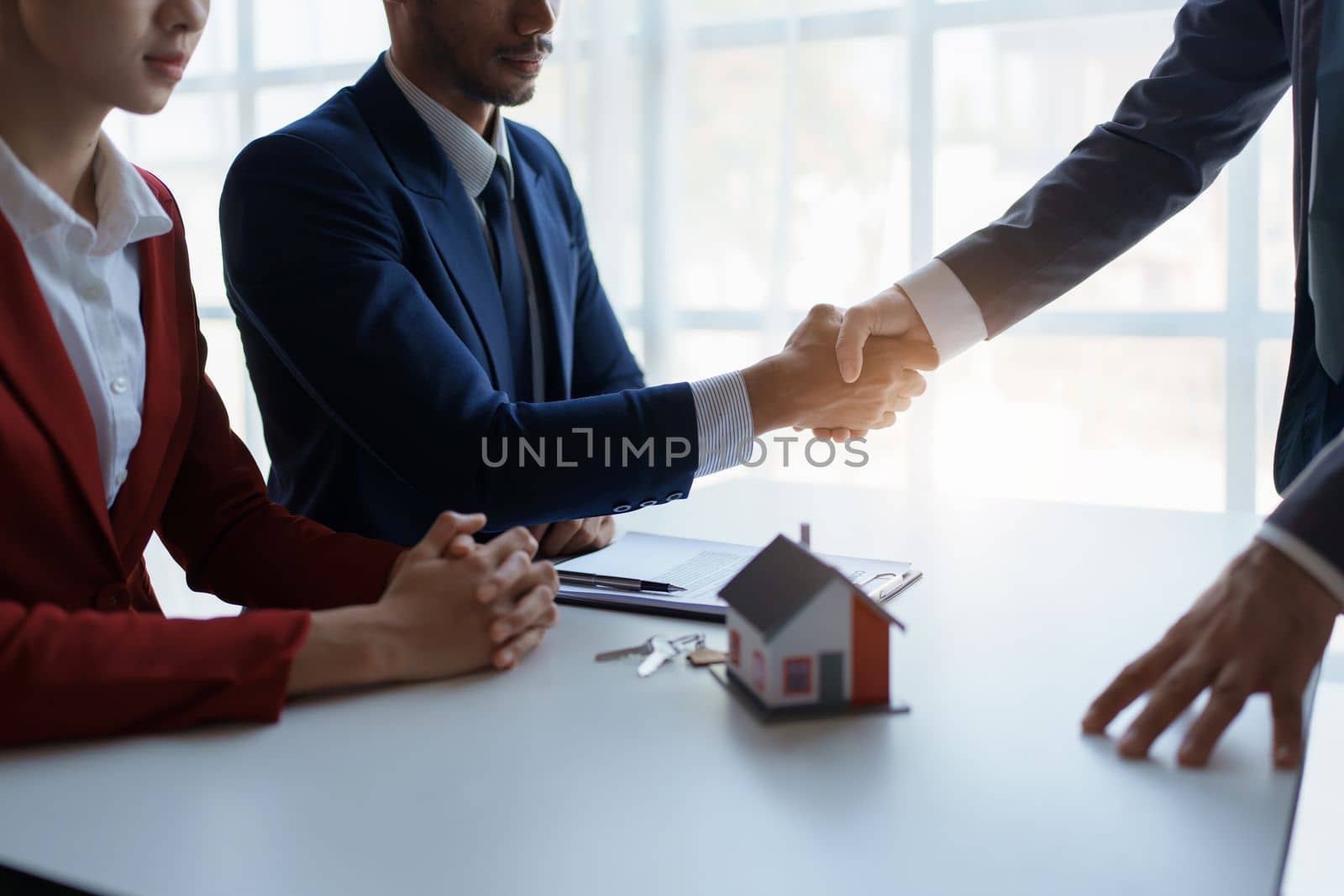 Asian real estate agent shaking hands handing over house and keys to his client's house after client sign contract