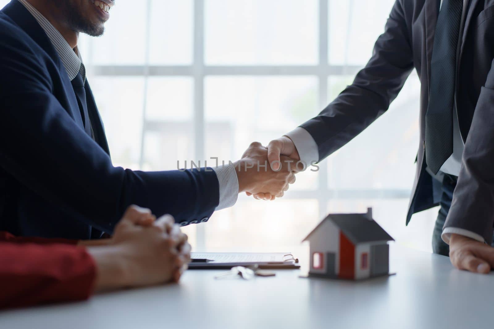 Asian real estate agent shaking hands handing over house and keys to his client's house after client sign contract