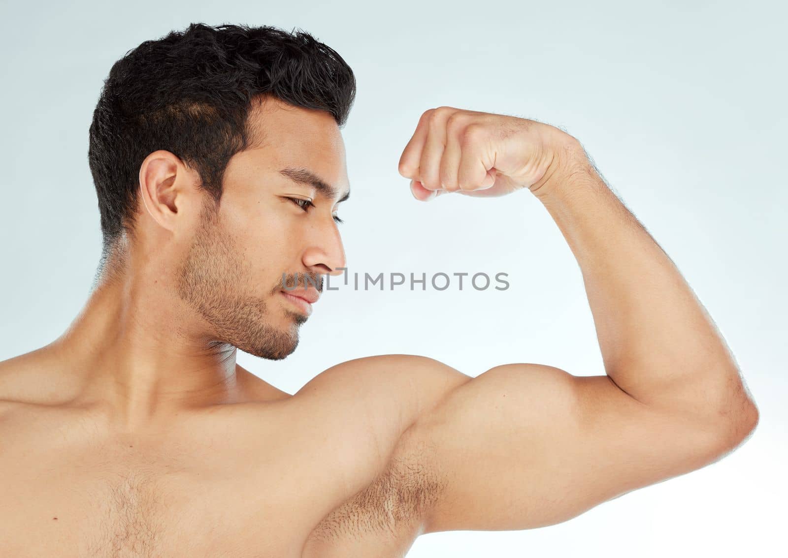 Muscles made of steel. a man flexing his biceps against a studio background. by YuriArcurs
