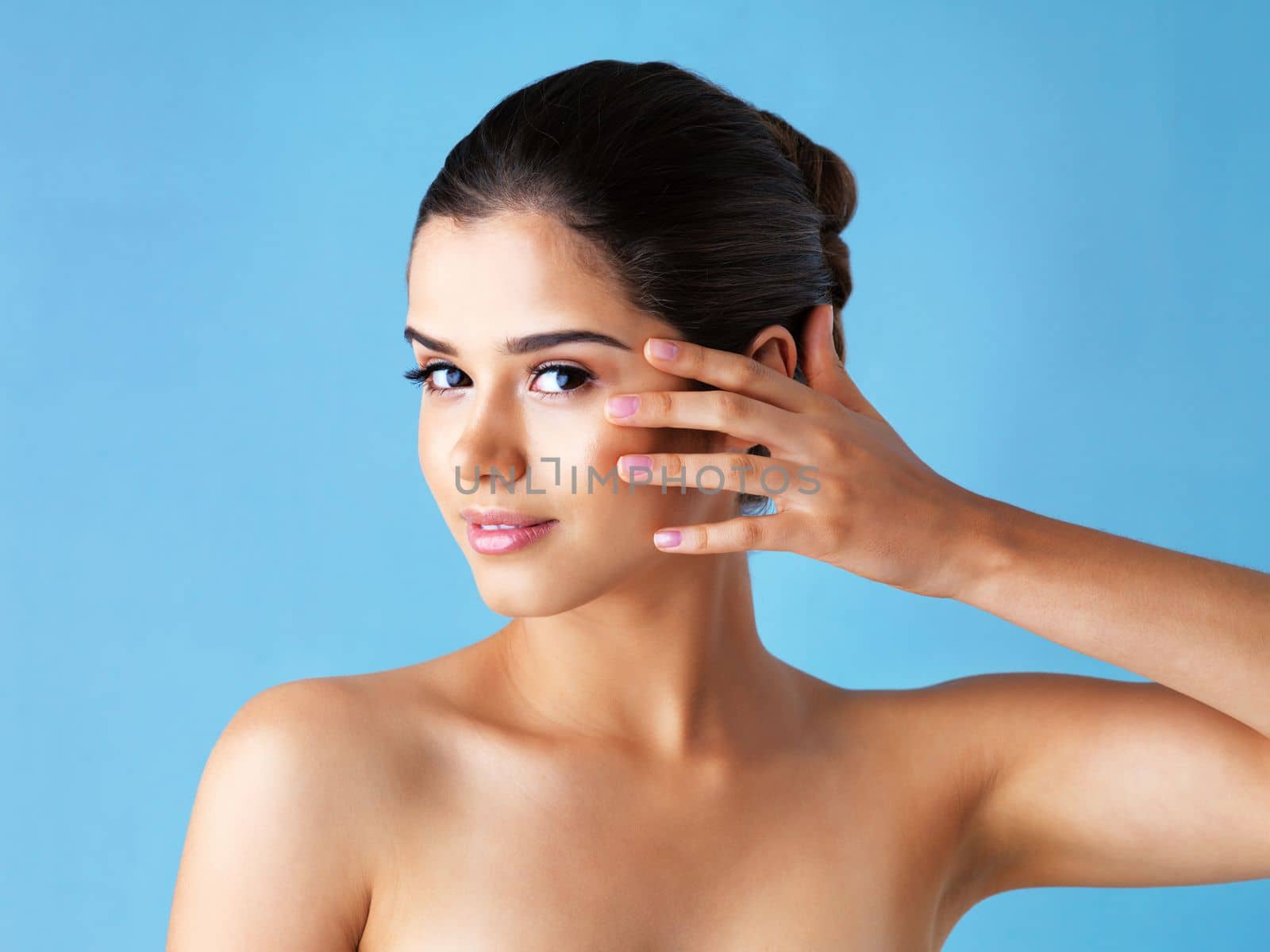 Who needs makeup with such flawless skin. Studio portrait of a beautiful young woman posing against a blue background