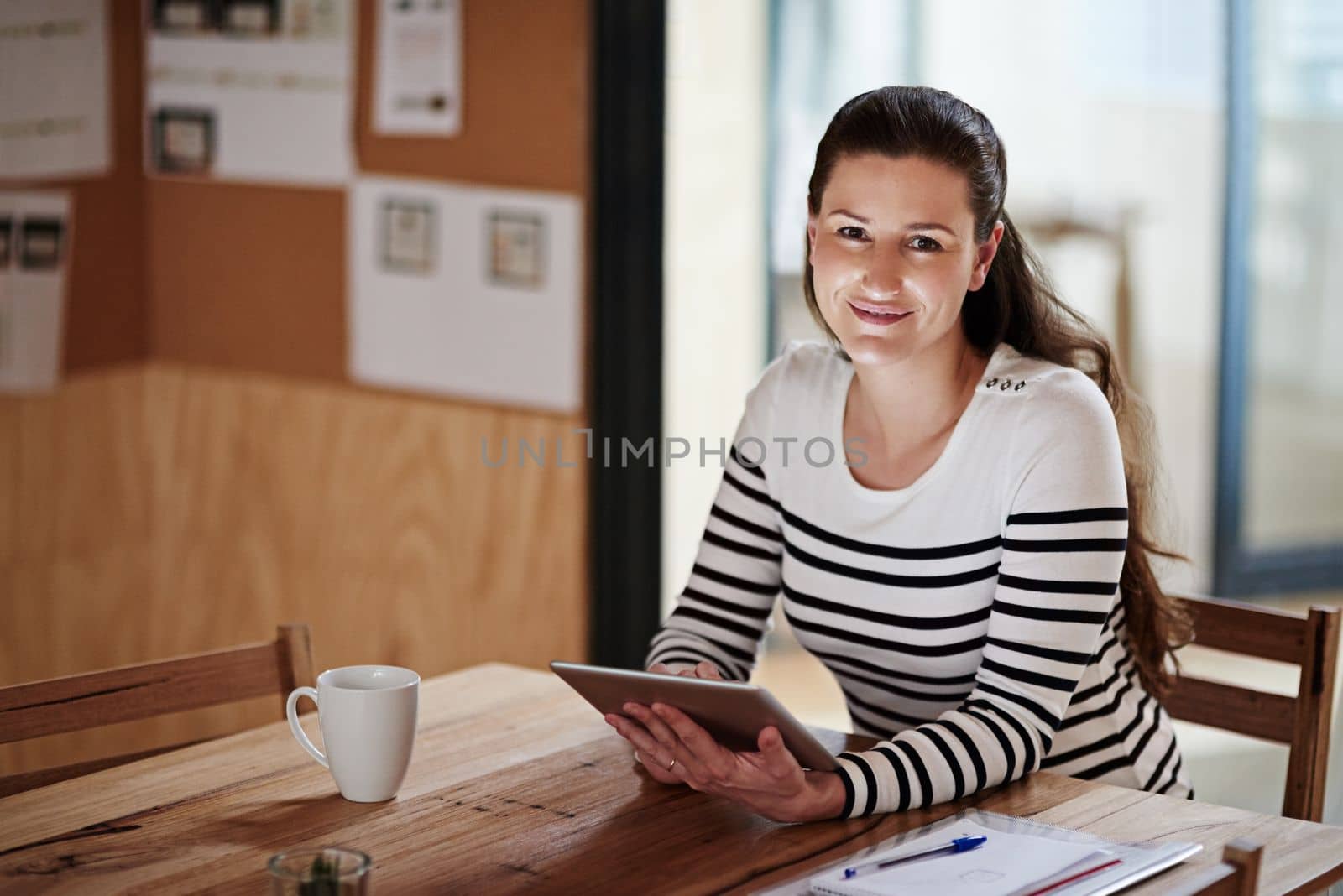 Staying connected in todays business world. Portrait of a young businesswoman using a digital tablet in an office. by YuriArcurs