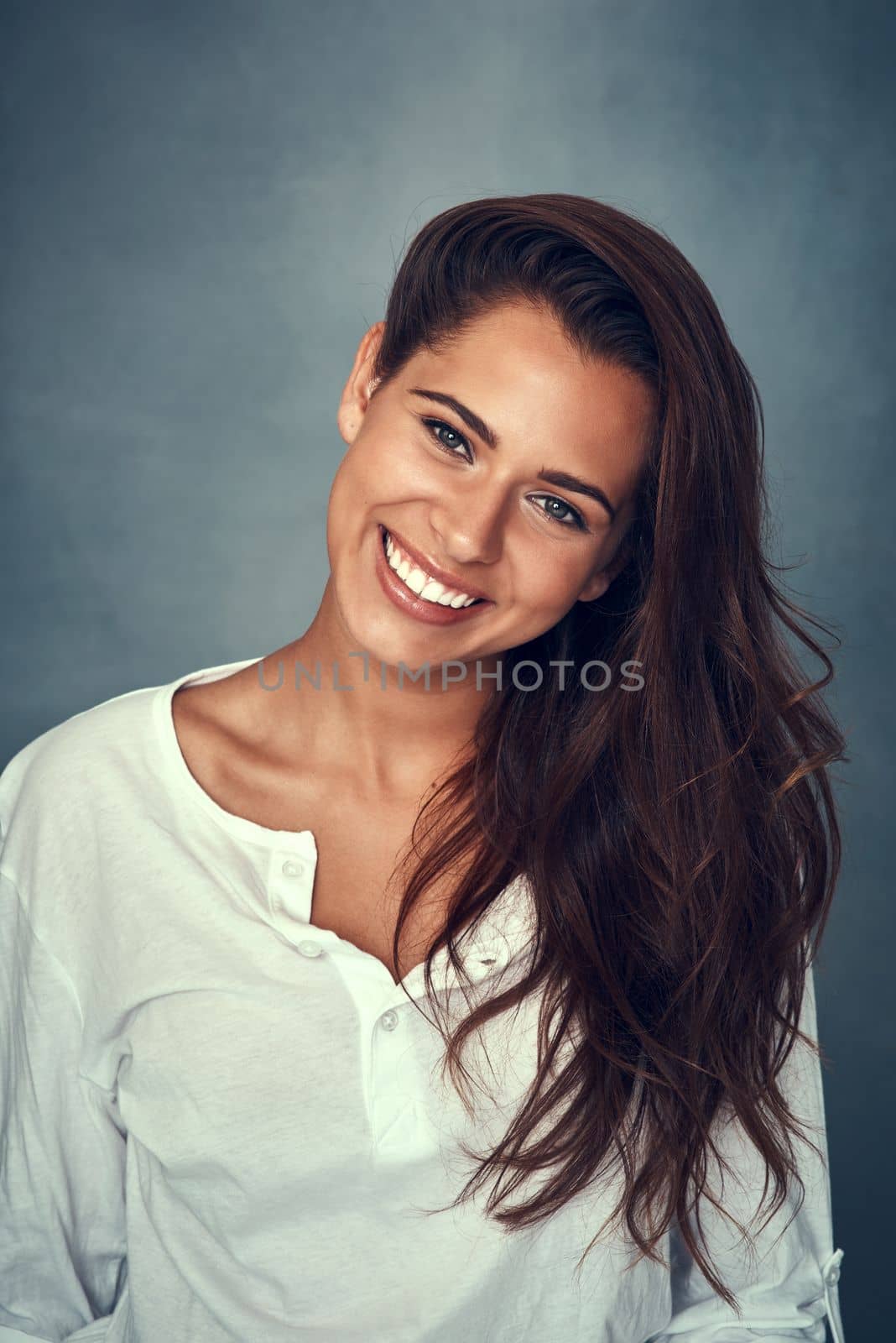 My smile is my favorite curve. Portrait of a beautiful young woman smiling against a gray background in studio. by YuriArcurs