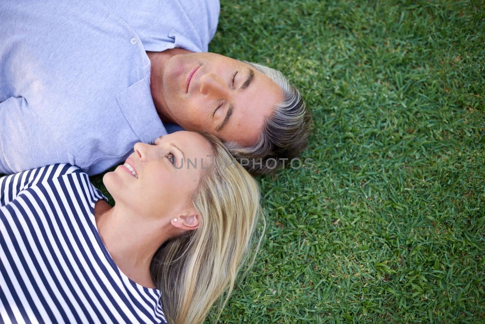 Their love comes naturally. High angle shot of a mature couple lying in the park. by YuriArcurs