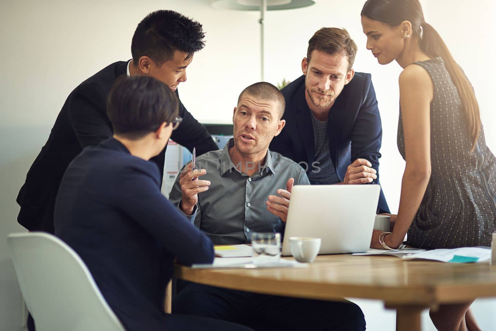Teamwork allows employees to take greater responsibility for decision making. a group of coworkers discussing something on a laptop during a meeting