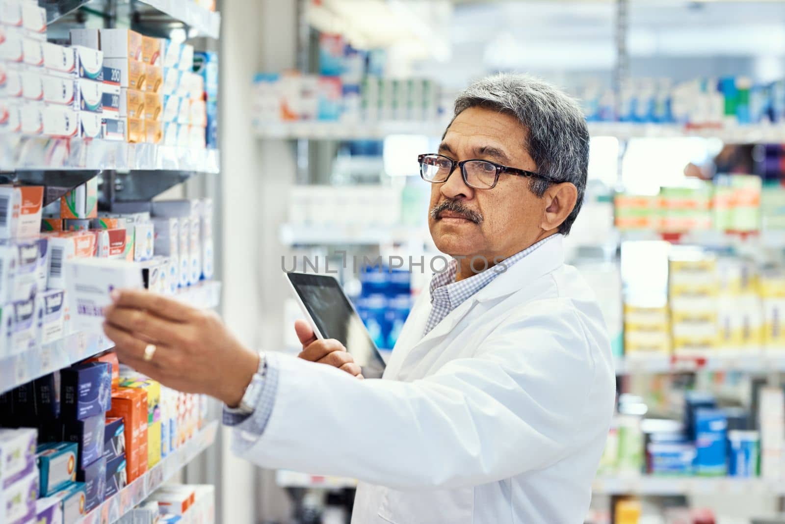 Deciding on what new stock to order. a mature pharmacist using a digital tablet while working in a chemist