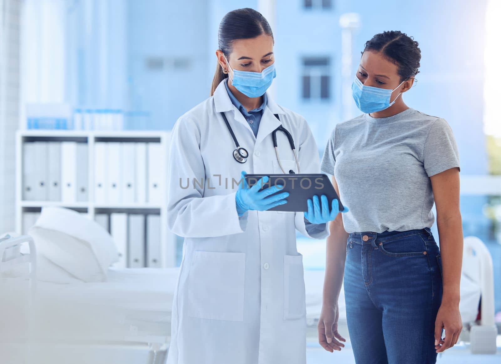 Doctor showing a patient corona virus test results on a tablet. Patient talking to doctor about covid test results. Physician in a consult using a wireless digital device. Gp using tablet by YuriArcurs