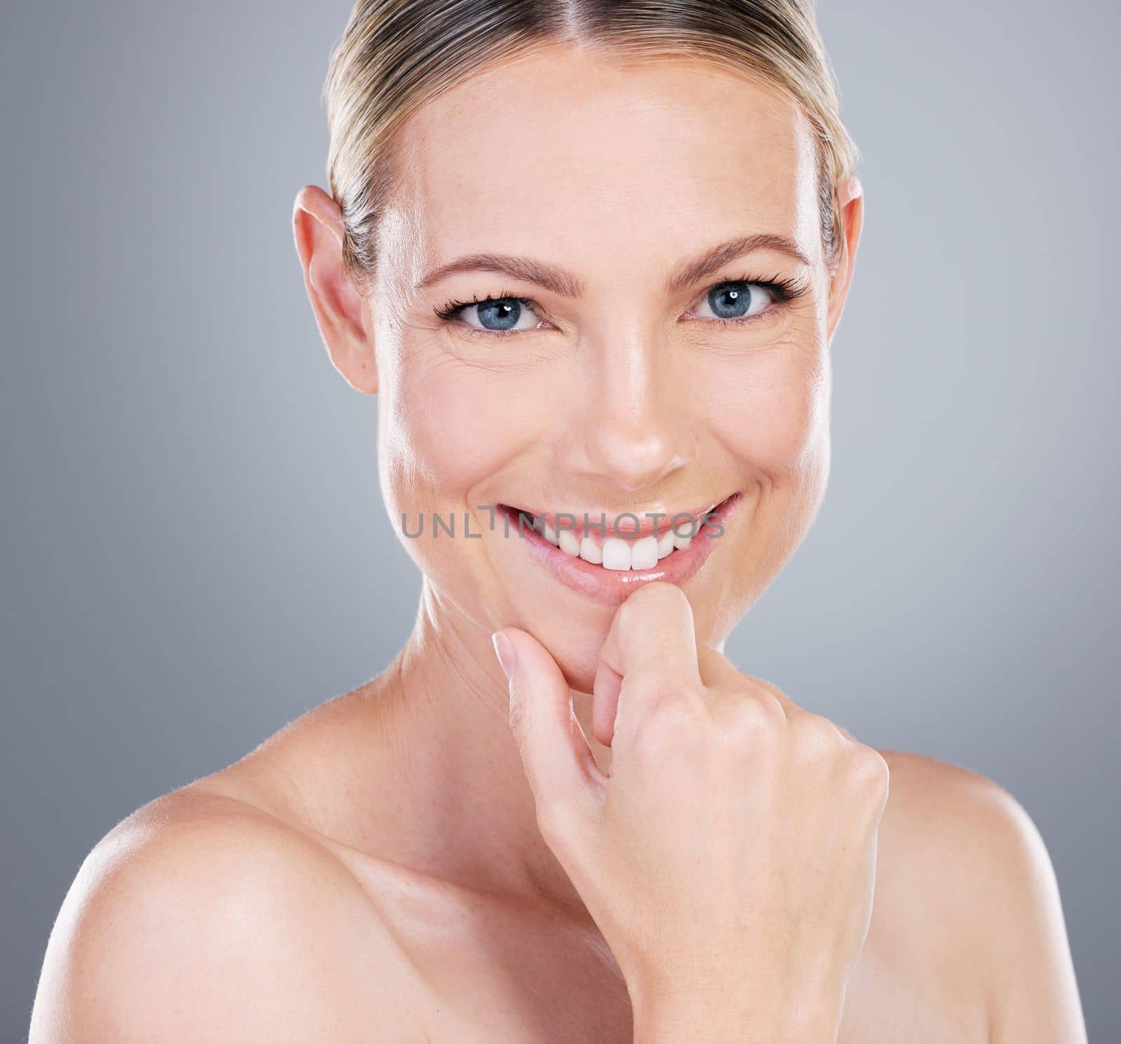 Stand out from the crowd. Studio portrait of an attractive mature woman touching her face against a grey background. by YuriArcurs