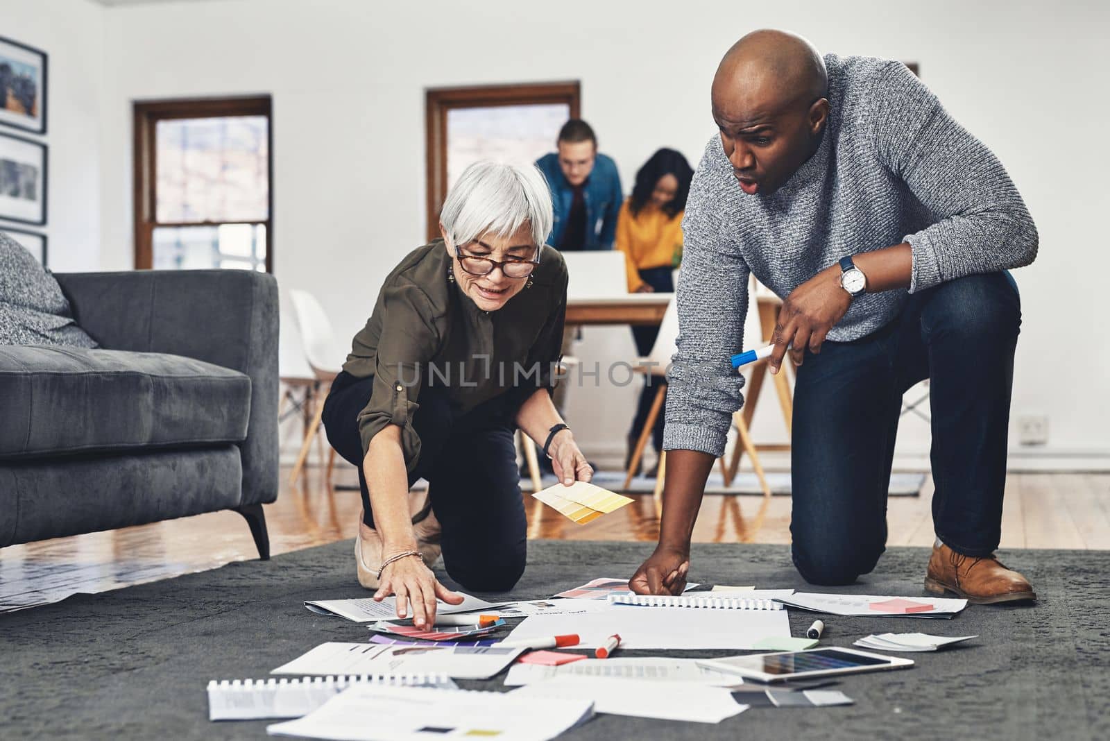 This setup is simple but effective. Full length shot of two businesspeople looking over paperwork while working on the floor of their office
