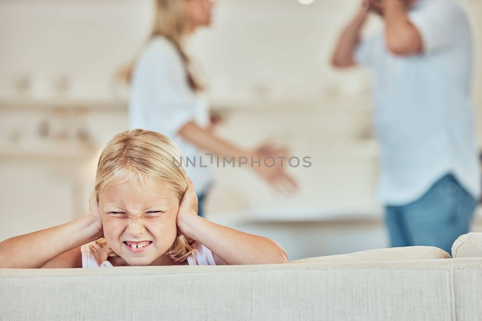 Sad little girl covering her ears with parents fighting in the background. Depressed child, parents arguing at home. Couple in conflict around their daughter. Stressed parents might end in divorce.