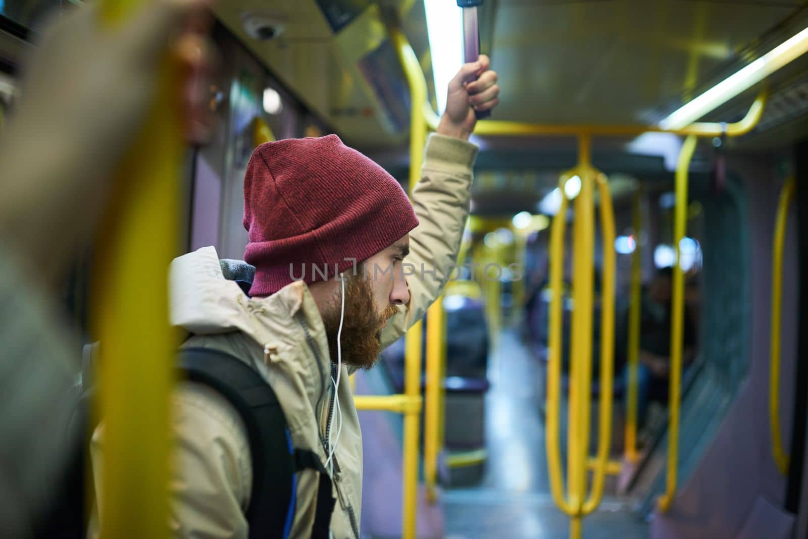 Just a little music to keep him company. a handsome young man listening to music on his cellphone while travelling on a bus